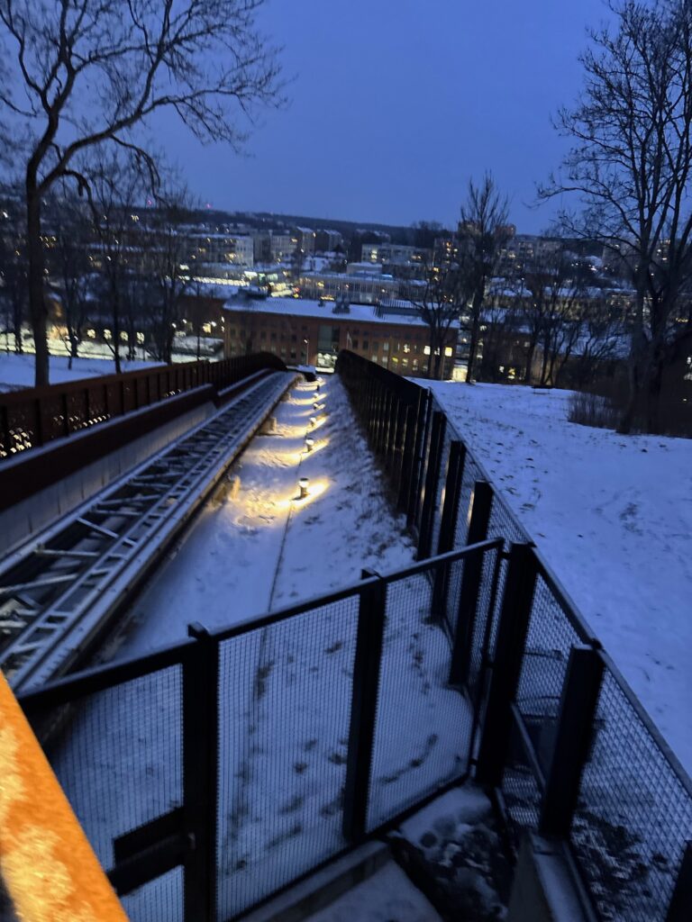 a snowy hill with a walkway and a train track