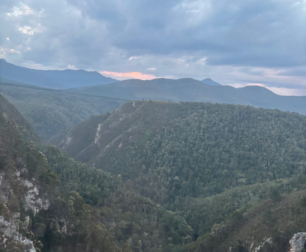 a mountain range with trees and clouds