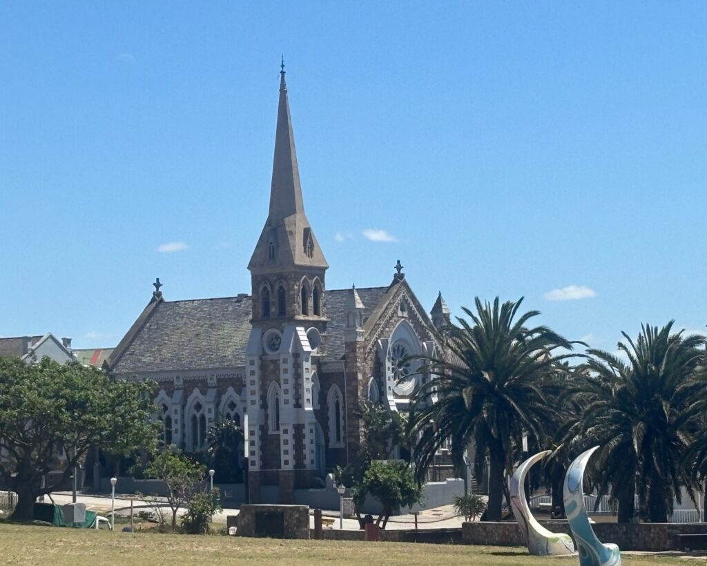 a church with a tall steeple and palm trees