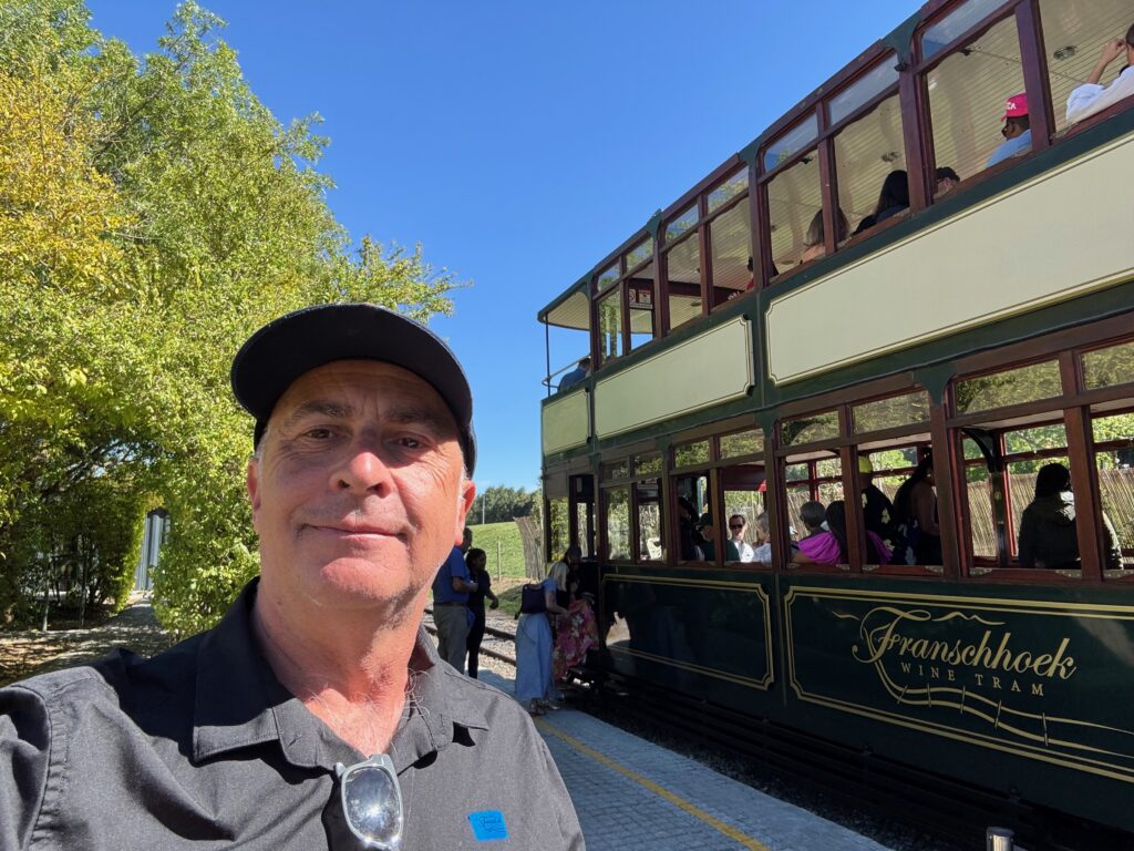 a man taking a selfie in front of a double decker bus