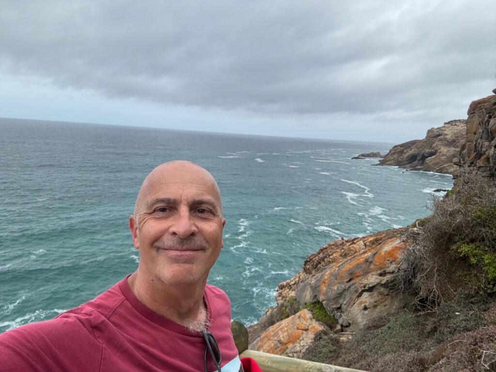 a man taking a selfie on a cliff overlooking the ocean