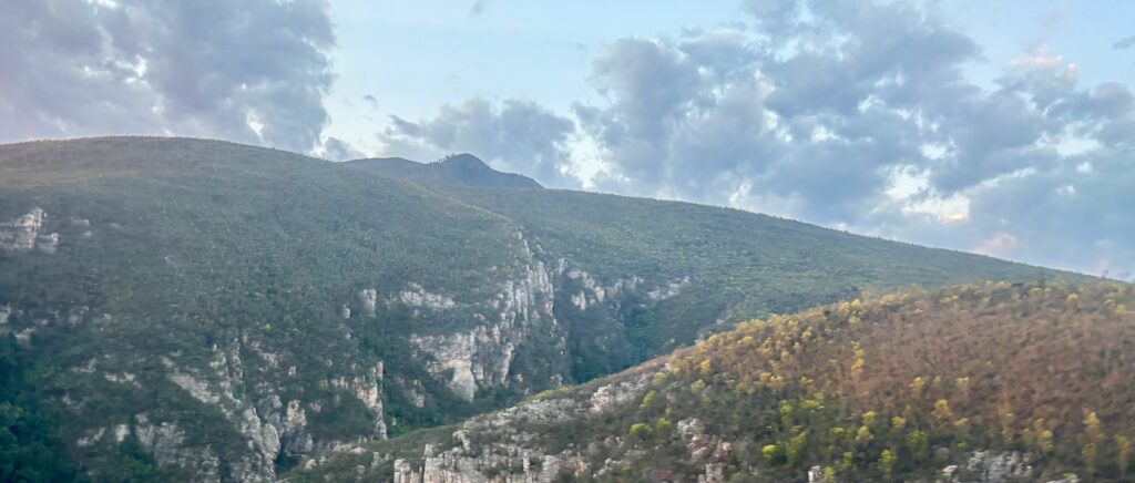 a mountain range with trees and clouds