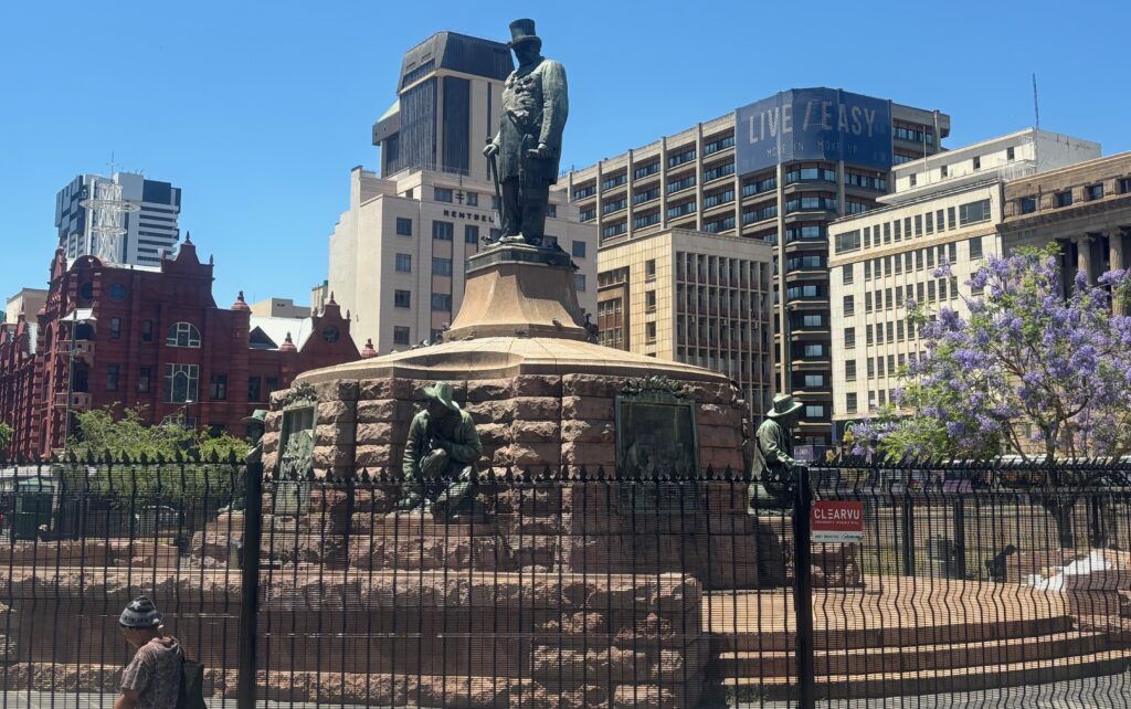 a statue of a man in a hat in front of a fence