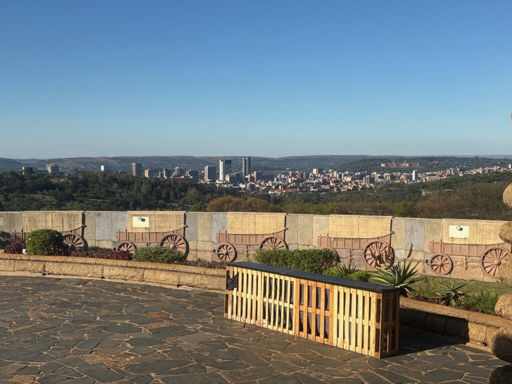 a stone wall with a fence and a city in the background